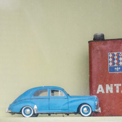 Detail in a window of an old car mechanic garage old miniature car collection Antar brand oil can in Ouzouer-le-Doyen