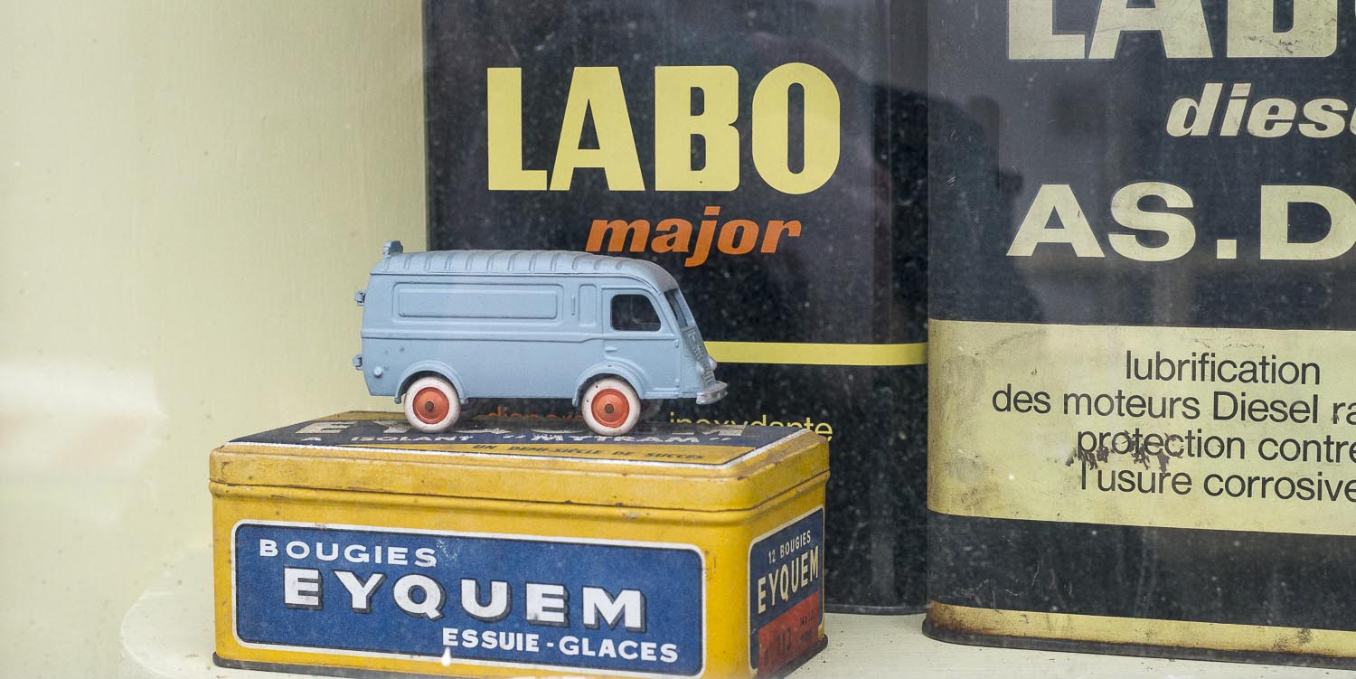 Detail in a window of one of the old car garages old miniature car collection Labo brand oil can in Ouzouer-le-Doyen