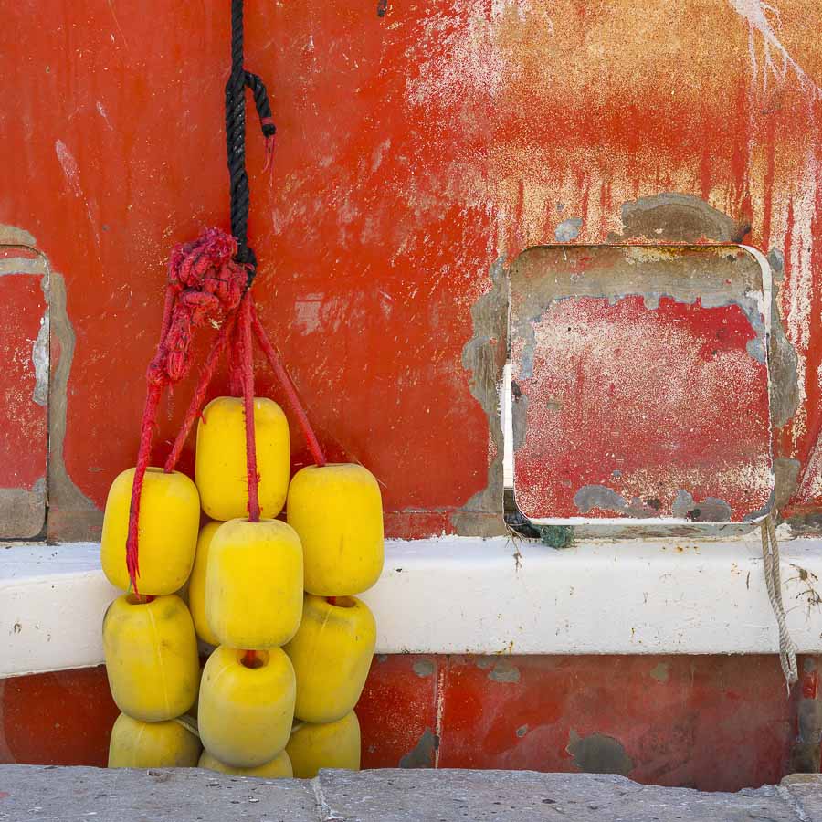 Détail d'un bateau rouge sur le bord du canal à Sète dans l'Hérault des flotteurs jaunes entre le bateau et le quai